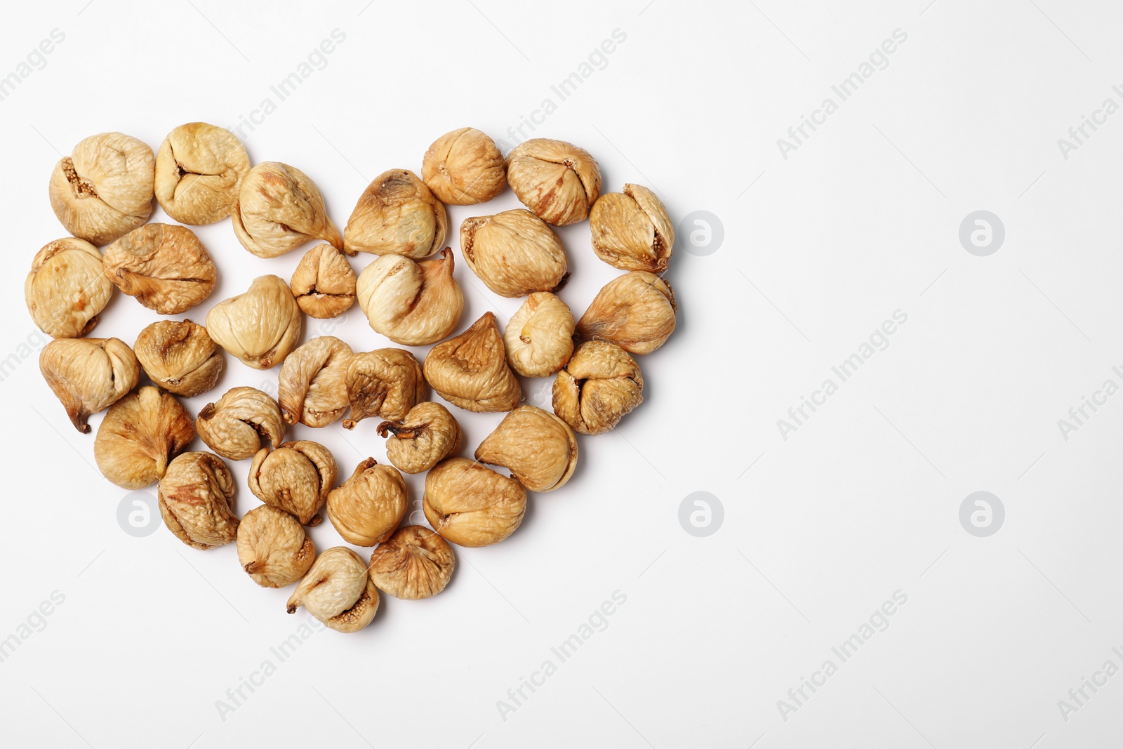 Photo of Heart shaped heap of dried figs on white background, top view with space for text. Healthy fruit