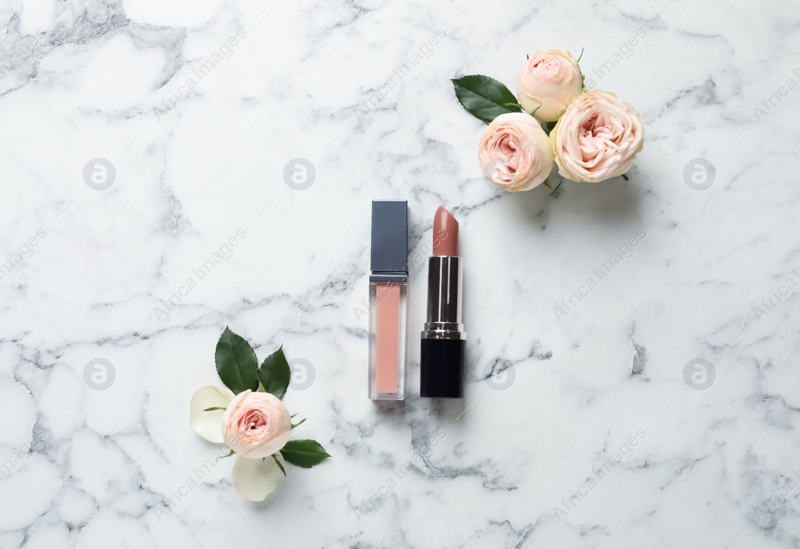 Photo of Lipstick and lip gloss with flowers on light background, flat lay