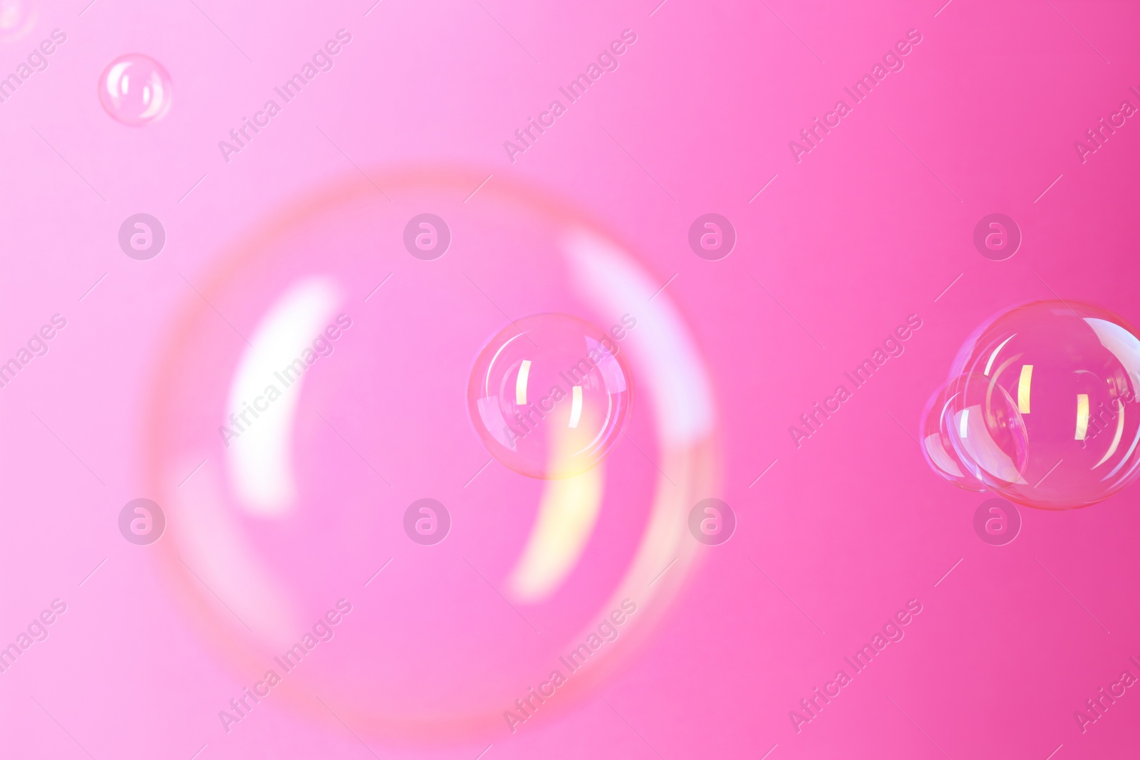 Photo of Beautiful transparent soap bubbles on pink background