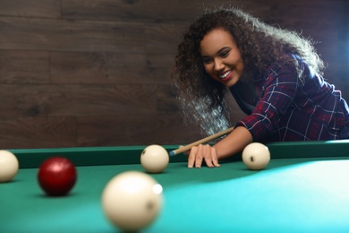 Photo of Young African-American woman playing billiard indoors