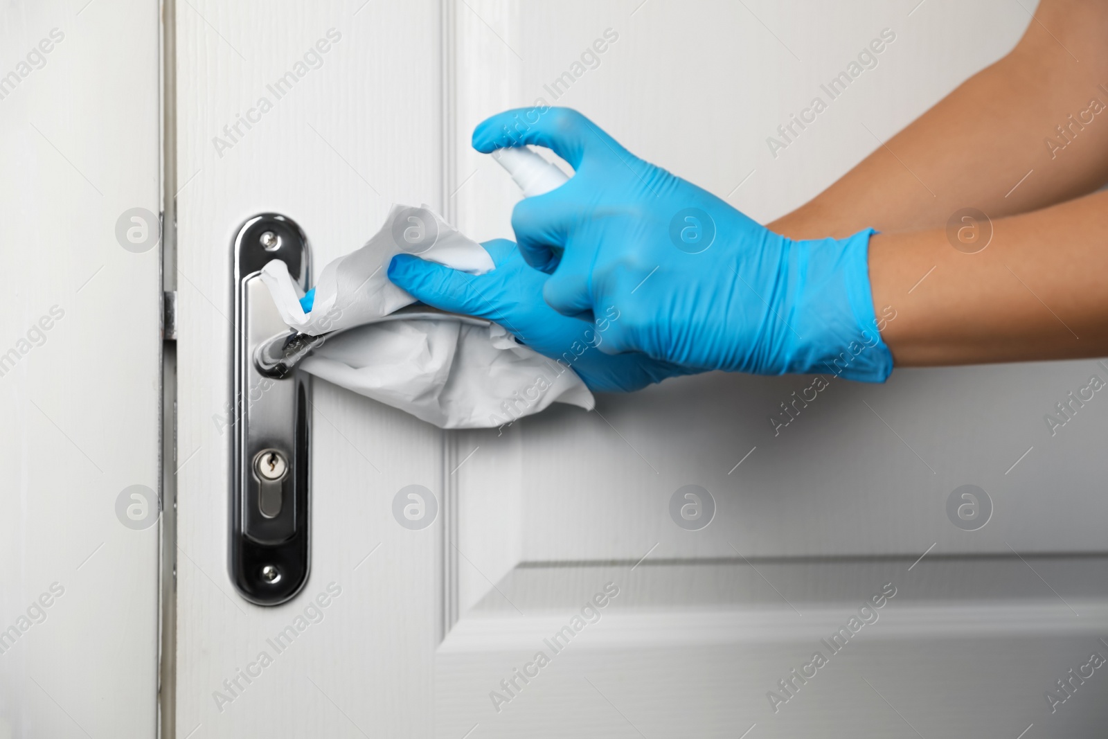 Photo of Woman cleaning door handle with antiseptic in office, closeup