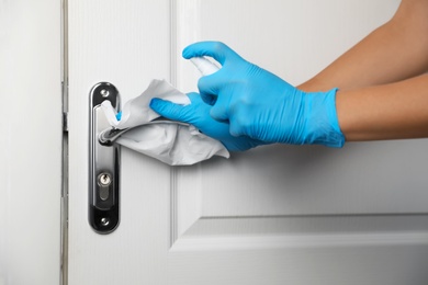 Photo of Woman cleaning door handle with antiseptic in office, closeup