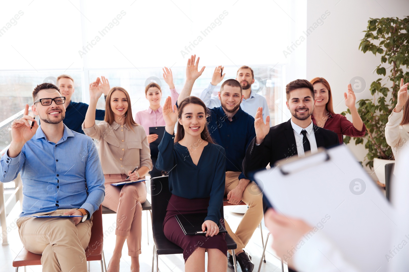 Photo of People raising hands to ask questions at business training indoors