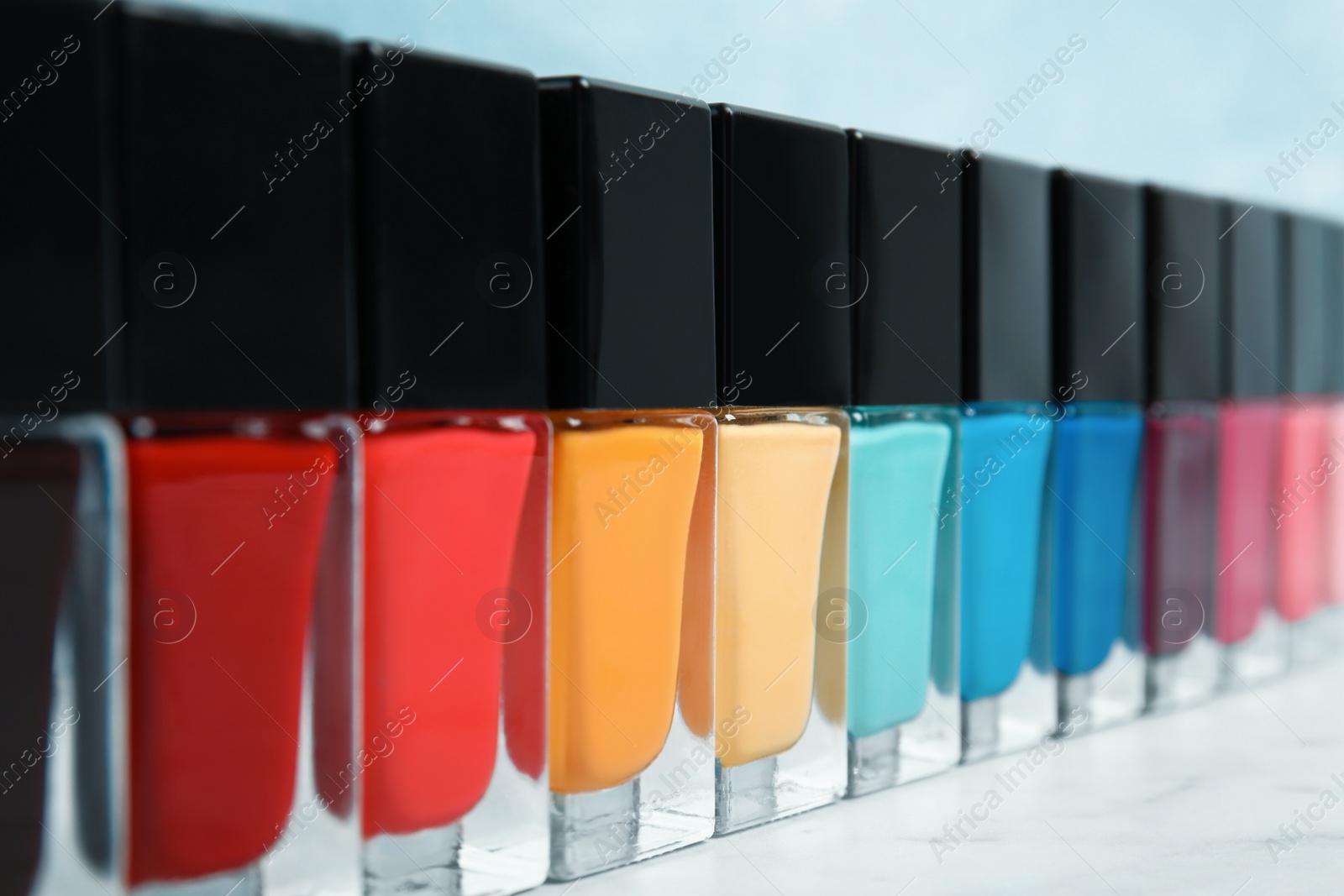 Photo of Bright nail polishes on table against color background, closeup