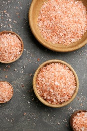 Photo of Pink himalayan salt in wooden bowls on grey table, flat lay