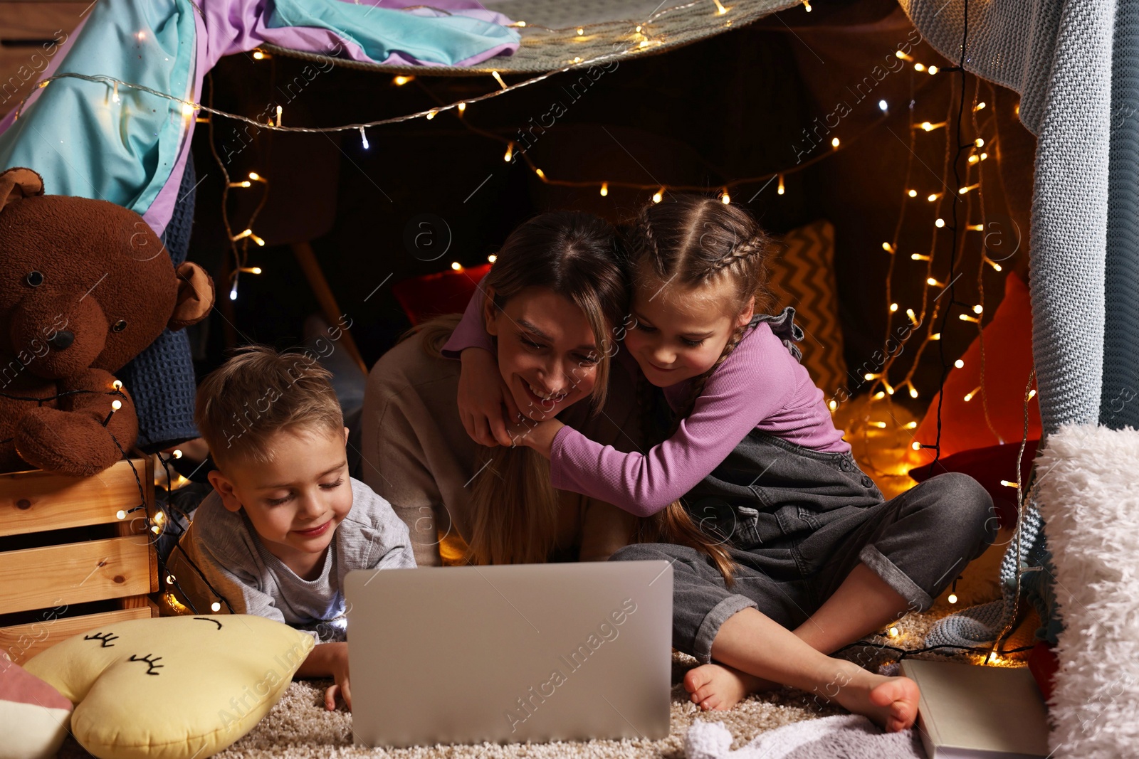 Photo of Mother and her children with laptop in play tent at home