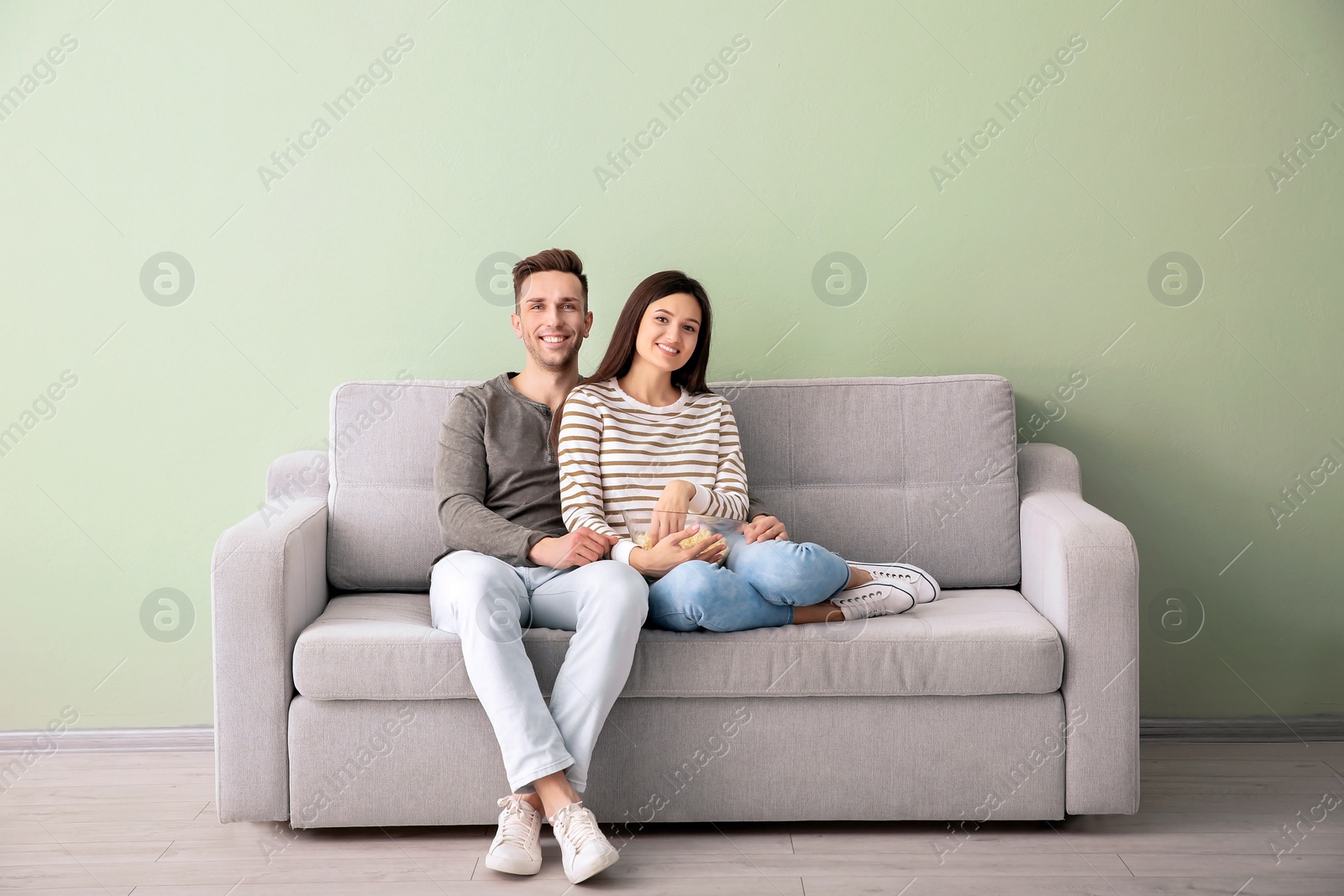 Photo of Happy young couple watching TV on sofa at home