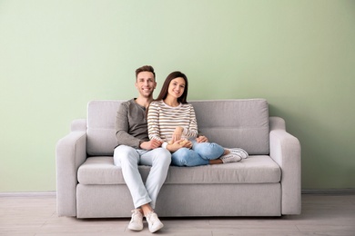 Happy young couple watching TV on sofa at home