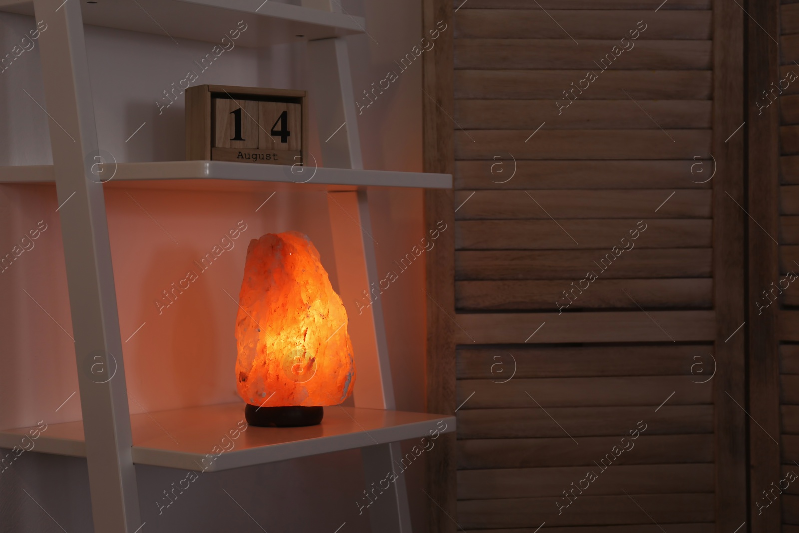 Photo of Himalayan salt lamp on shelf in dark room