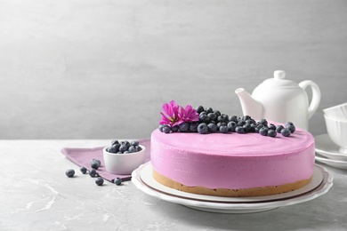 Plate with tasty blueberry cake on light grey table. Space for text