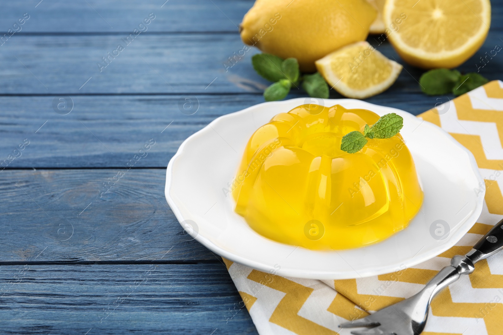 Photo of Plate with lemon jelly and mint served on blue wooden table. Space for text