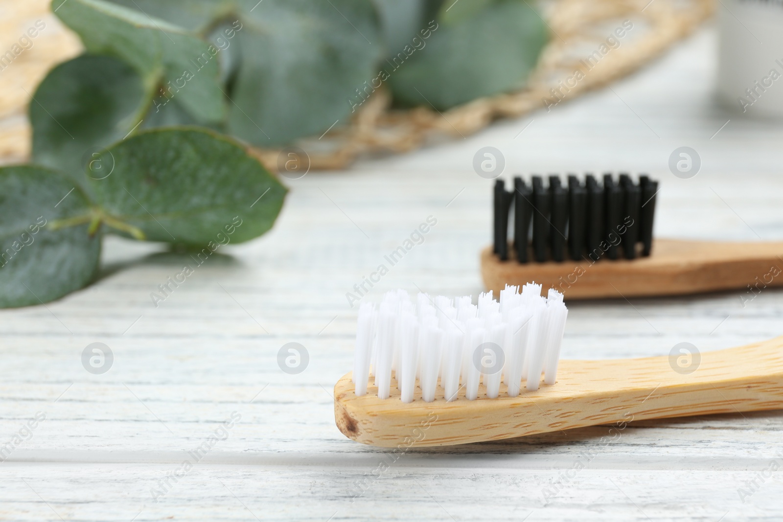 Photo of Bamboo toothbrushes on white wooden table, closeup. Space for text