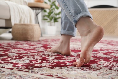 Photo of Woman standing on carpet with pattern at home, closeup. Space for text