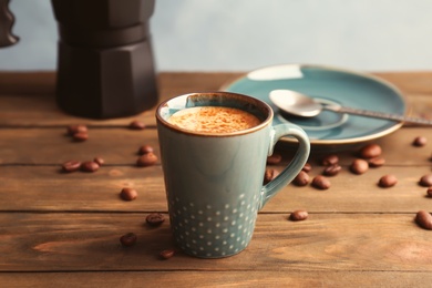 Cup of aromatic hot coffee and beans on wooden table