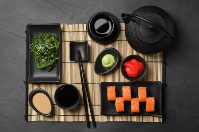 Tasty sushi rolls served on black table, flat lay