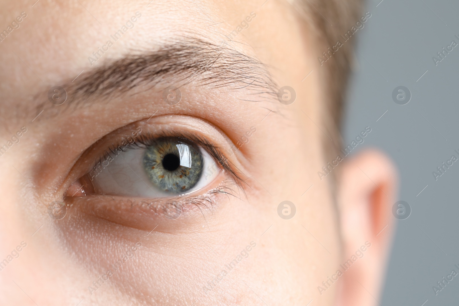 Photo of Perfect vision. Man with beautiful eyes on grey background, closeup