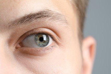 Photo of Perfect vision. Man with beautiful eyes on grey background, closeup