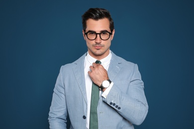 Photo of Portrait of handsome young businessman wearing glasses on blue background