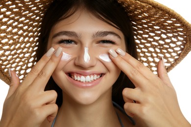 Photo of Teenage girl applying sun protection cream on her face against white background, closeup