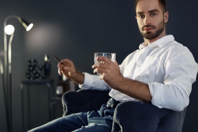Photo of Man with glass of whiskey and cigar sitting at table. Space for text
