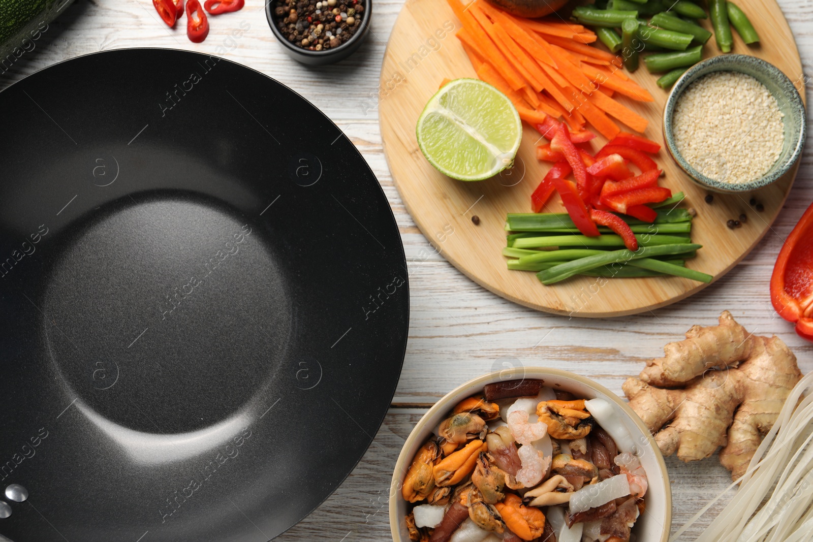 Photo of Flat lay composition with black wok and products on light wooden table