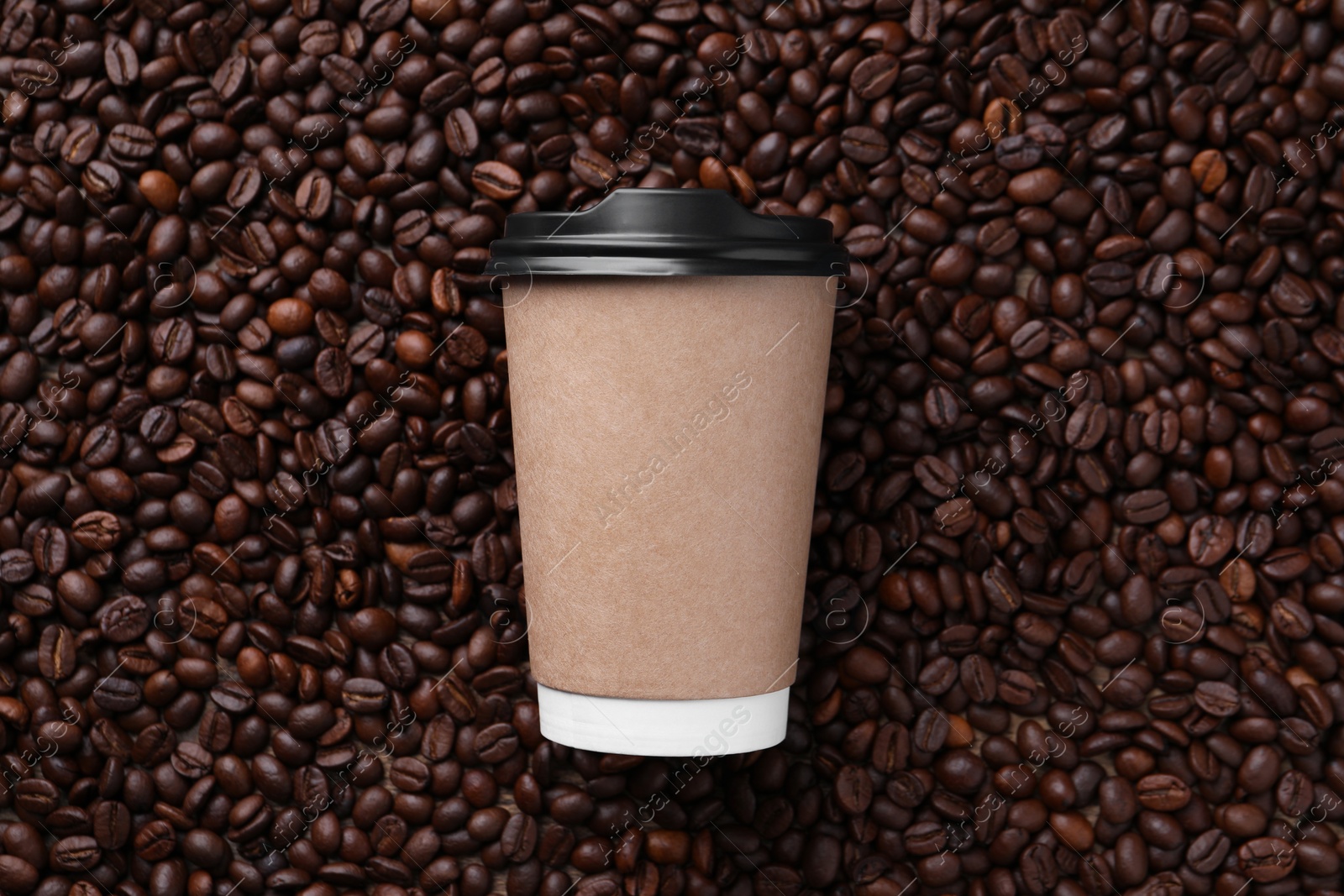 Photo of Coffee to go. Paper cup on roasted beans, top view