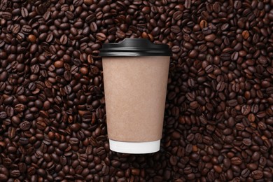 Photo of Coffee to go. Paper cup on roasted beans, top view