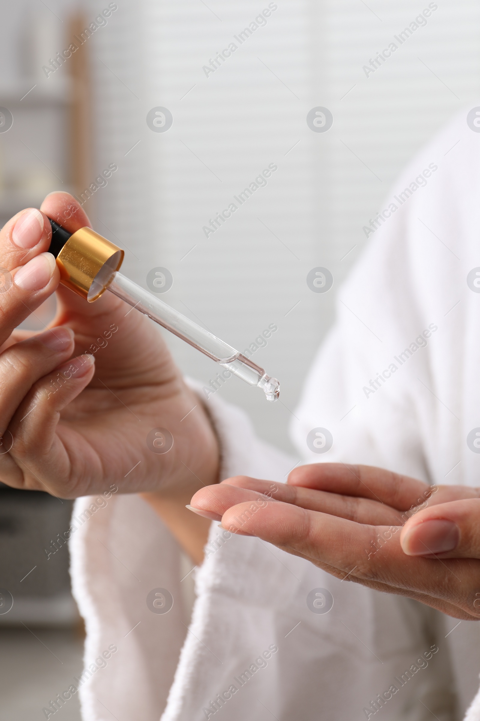 Photo of Woman applying cosmetic serum onto her hand on blurred background, closeup