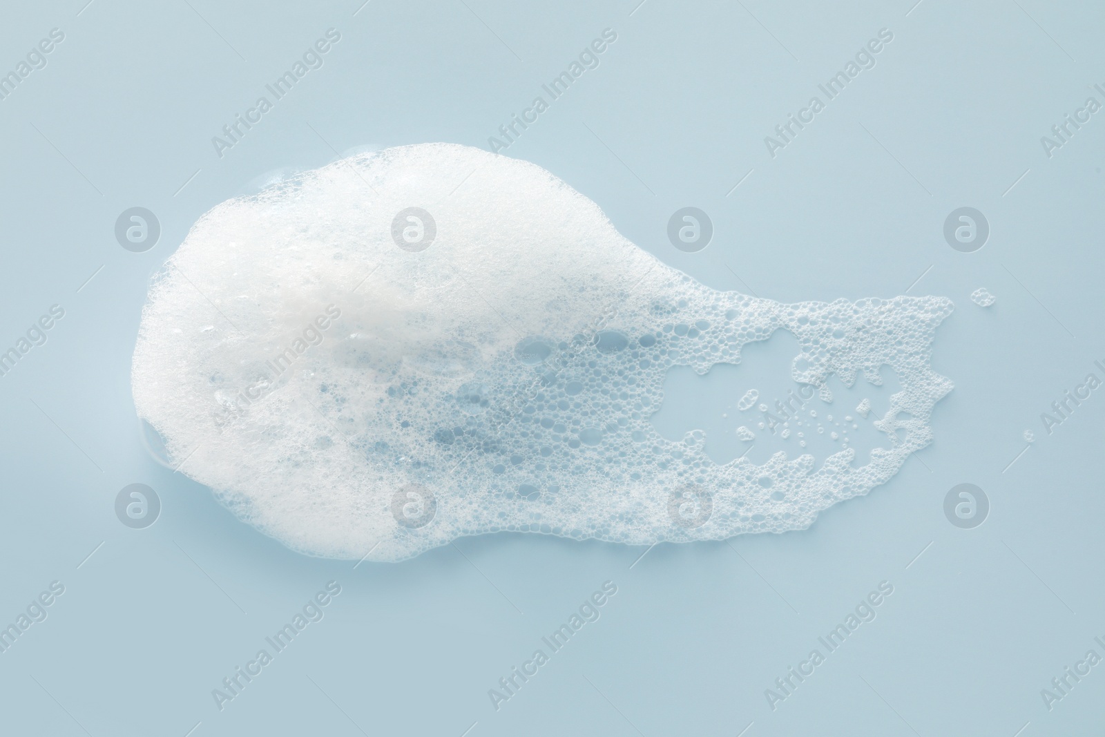 Photo of Smudge of white washing foam on color background, top view