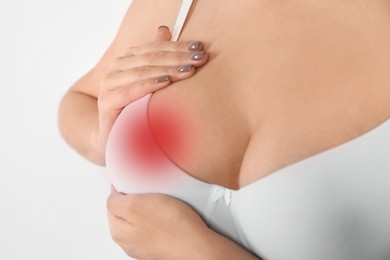 Woman checking her breast on white background, closeup