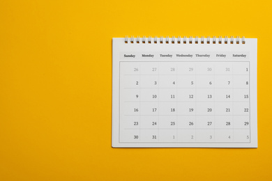 Photo of Paper calendar on yellow background, top view. Space for text