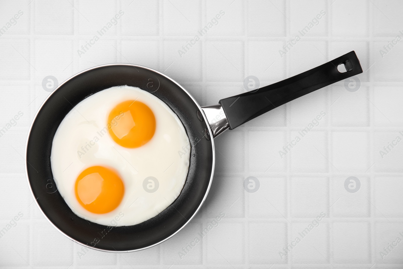 Photo of Tasty fried eggs in pan on white table, top view