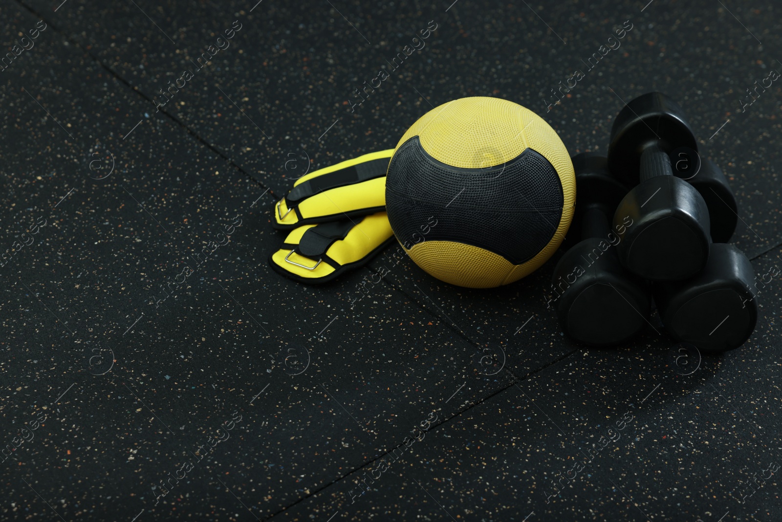Photo of Yellow medicine ball, weighting agents and dumbbells on floor, space for text