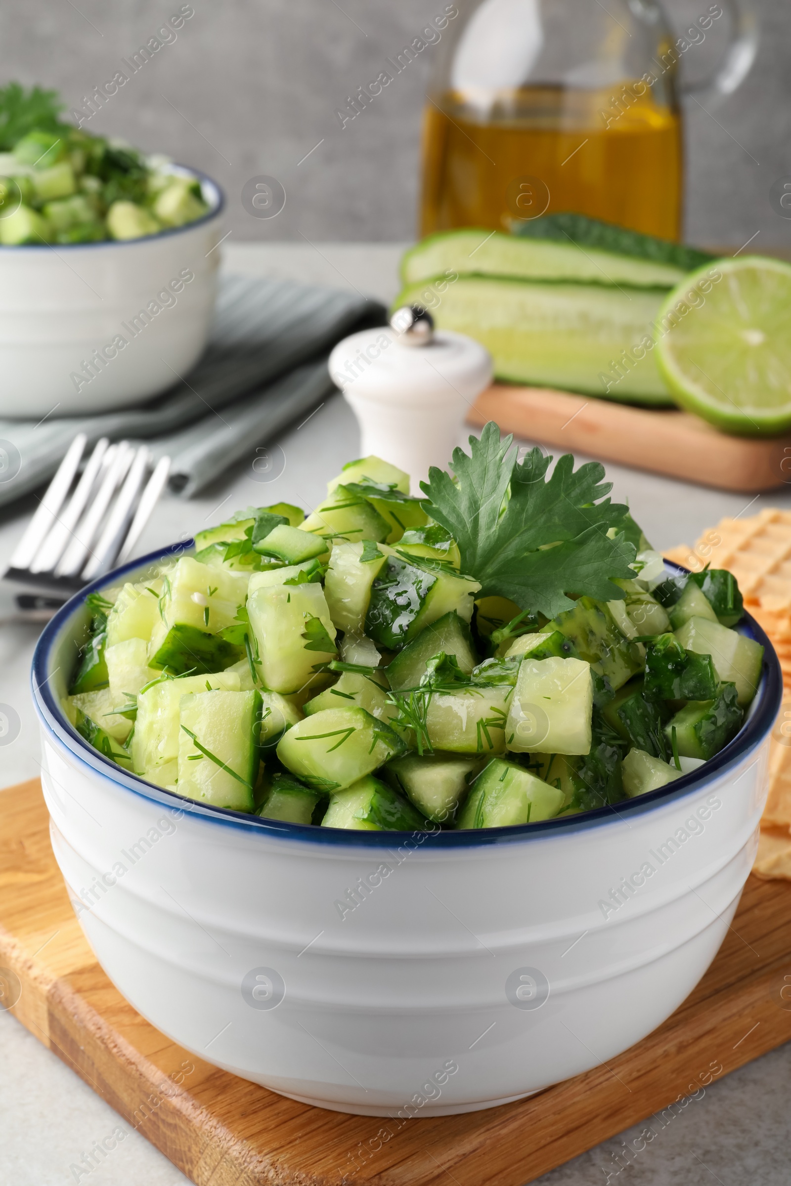 Photo of Bowl of delicious cucumber salad served on light table
