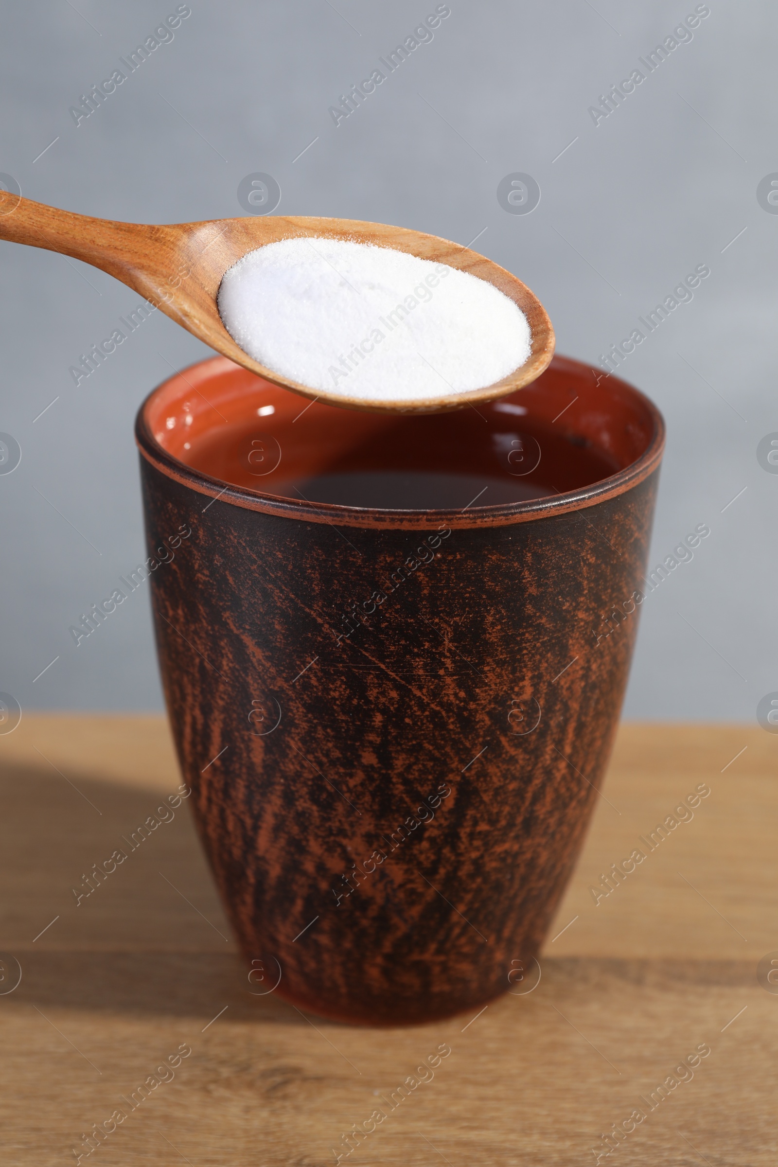 Photo of Spoon with baking soda over glass of water on wooden table