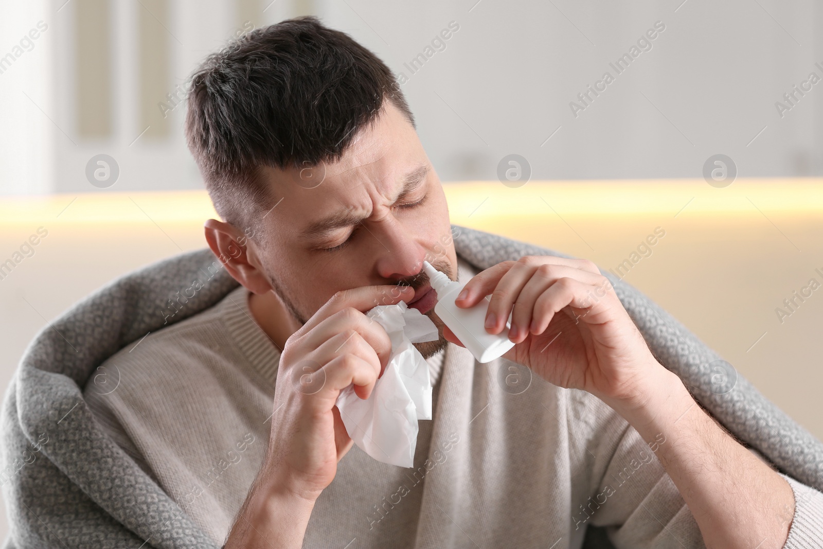 Photo of Ill man using nasal spray at home