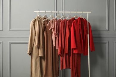 Rack with different stylish women`s clothes near grey wall