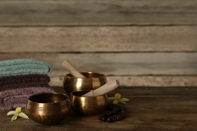 Photo of Composition with golden singing bowls on wooden table, space for text