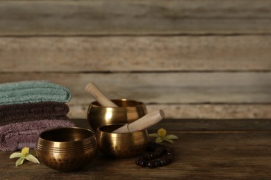 Composition with golden singing bowls on wooden table, space for text