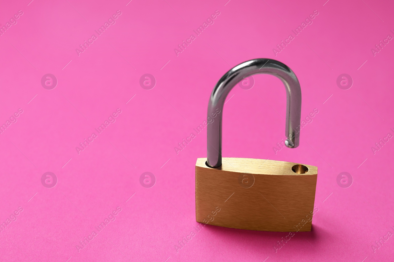 Photo of One steel padlock on pink background, closeup. Space for text