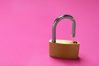 Photo of One steel padlock on pink background, closeup. Space for text