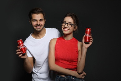 Photo of MYKOLAIV, UKRAINE - NOVEMBER 28, 2018: Young couple with Coca-Cola cans on dark background