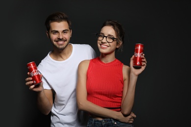 MYKOLAIV, UKRAINE - NOVEMBER 28, 2018: Young couple with Coca-Cola cans on dark background