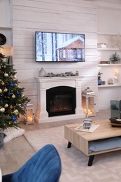 Stylish living room interior with modern TV, fireplace and Christmas tree