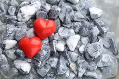 Photo of Red decorative hearts on stones and water, top view. Space for text