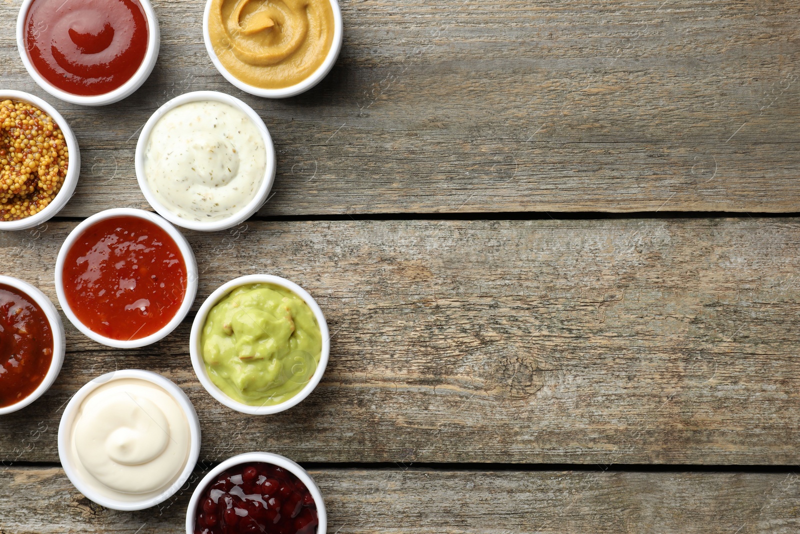 Photo of Different tasty sauces in bowls on wooden table, flat lay. Space for text