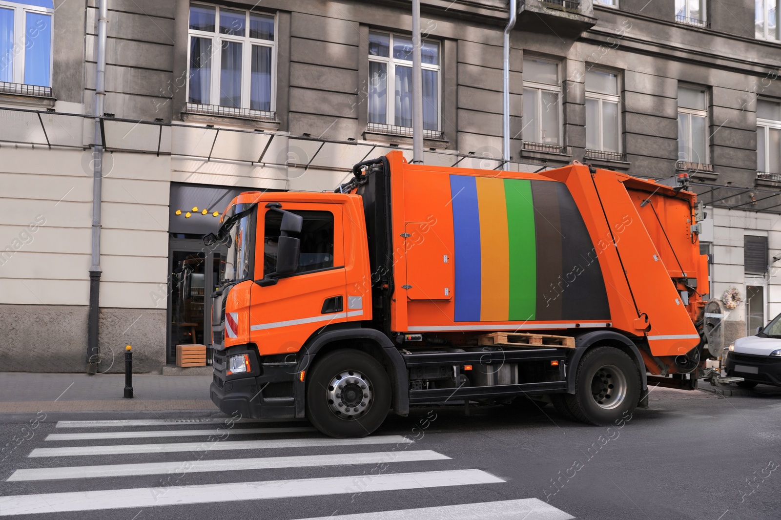 Photo of Modern orange garbage truck on city road outdoors