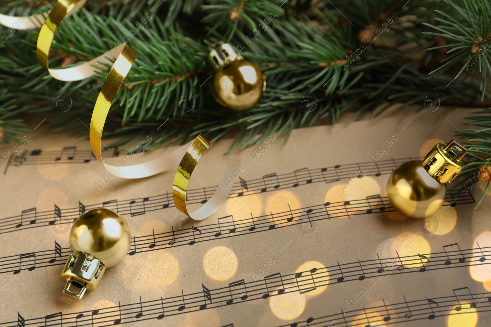 Image of Christmas and New Year music. Fir tree branch and festive decor on music sheets, bokeh effect