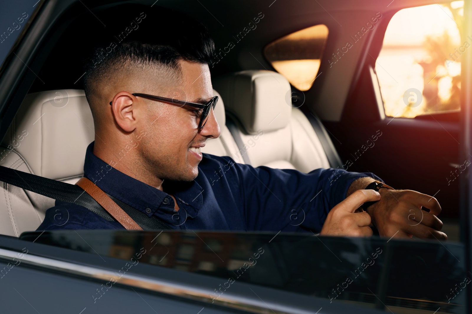 Photo of Businessman checking time on backseat of modern taxi