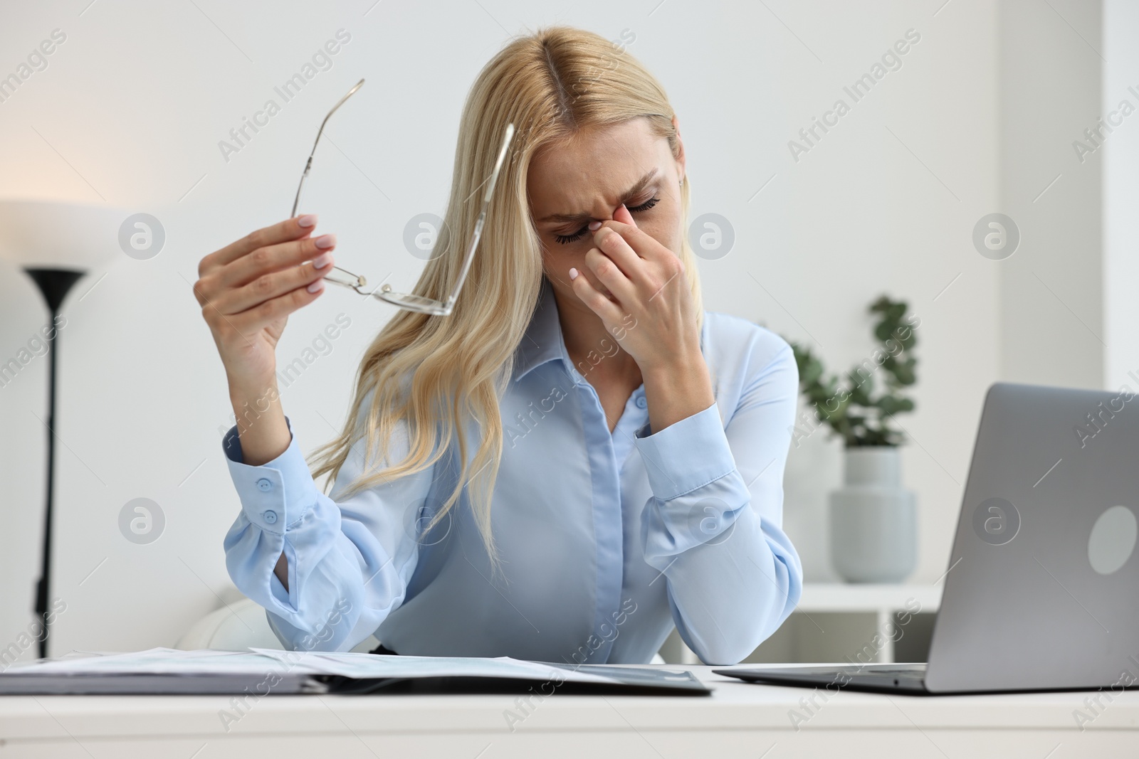 Photo of Overwhelmed woman with glasses at table in office